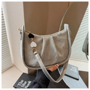 Détail du sac à bandoulière en daim gris avec texture plissée et breloques en cœur