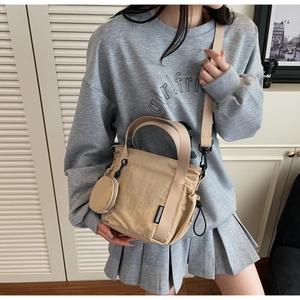 Detail of khaki nylon crossbody bucket bag with small round coin purse accessory