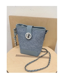 Detail view of denim texture bucket bag with silver peanut charm and chain strap