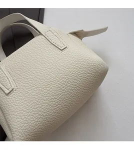 Détail de la texture cuir grainé blanc et des surpiqûres nettes du petit sac à main