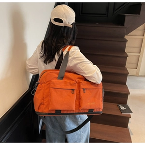 Detail of orange travel bag with dual zip pockets and adjustable shoulder strap