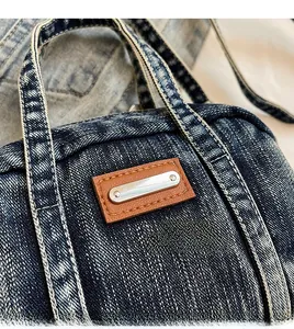 Close-up of vintage blue denim bag featuring brown leather patch and metallic accents