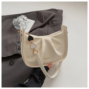 Détail du sac seau plissé crème avec chaîne à pendentif cœur et bandoulière