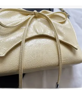 Detailed view of the creamy bow accent and wrinkled oil wax leather texture of the bag