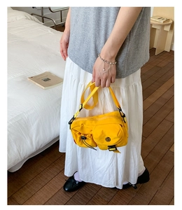 Detail showing bright yellow nylon crossbody bag with multi-pocket and drawstring design