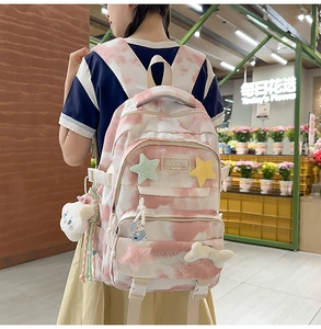 Detail view of pink tie-dye backpack with cute plush star patch and cartoon charms