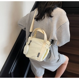 Detail of beige nylon bucket bag with detachable round coin purse and logo tag