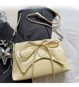 Close-up of cream bow-knot pleated handbag with golden chain and starfish charm