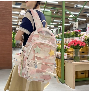 Detail of pink tie-dye backpack with plush cloud charms and multiple zip pockets