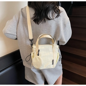 Detail of light beige nylon bucket bag with a detachable coin purse and adjustable strap