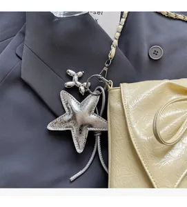 Detailed view of silver balloon dog and star charms on a yellow wrinkled chain bag
