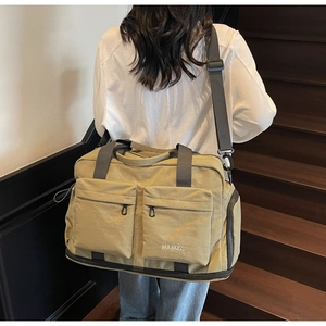 Detail view of khaki multi-pocket travel bag with durable straps and large front zip pockets