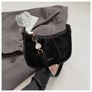 Détail du sac à épaule en daim noir avec chaîne en cœur et design plissé élégant