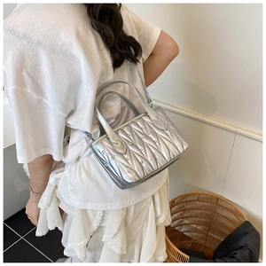 Detail of silver pleated bucket bag with rhinestone accents worn by a model from behind