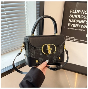 Detalle de bolso en cuero texturizado negro con cierre giratorio dorado y diseño de oso