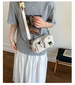Detail view of multi-pocket canvas crossbody bag with adjustable strap and buckle closure