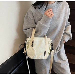 Detail of beige nylon tote bag with drawstring, mini coin purse and shoulder strap