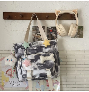 Detail of tie-dye backpack featuring decorative buckle and soft cloud plush pendant