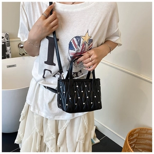 Detail of a black quilted chain bucket bag with silver rhinestones on a female model