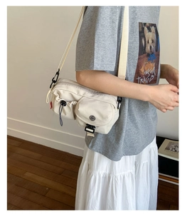 Detail of a beige casual crossbody bag with multiple pockets and black buckle closure