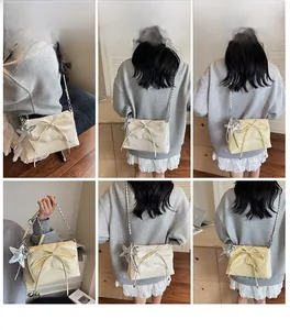 Vue détaillée du sac crème avec grand nœud et breloque étoile argentée sur la bandoulière