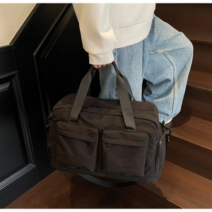 Close-up of black travel bag showing dual front pockets and MULAIDISS branding on steps