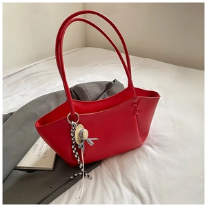Detail of red pebbled leather tote bag with straw hat pendant and checkered ribbon decor