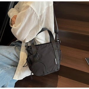 Detail of black nylon sports crossbody bag with a detachable round coin purse on a model