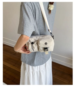 Detail view of beige nylon crossbody bag featuring utility pockets and functional buckles