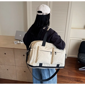 Detail of beige travel bag showing functional front pockets and adjustable strap for sports