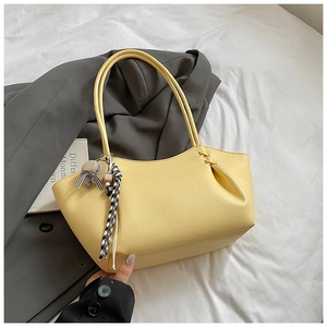 Close-up of yellow lychee leather tote bag with black and white checkered ribbon detail