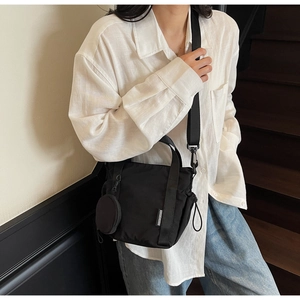 Detail view of a black nylon bucket bag with adjustable strap and small round coin purse