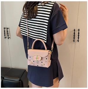 Detalle de bolso rosa de cuero sintético con estampado de oso, cierre dorado y bandolera