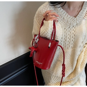Detail of red glossy leather bucket bag with white fashion text and matching charm