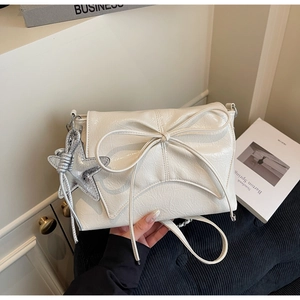 Détail du sac à rabat blanc crème avec grand nœud et pendentif étoile en argent