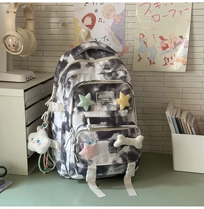 Detail of tie-dye backpack featuring cute plush pendants in a cozy dorm room setting