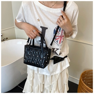 Close-up of a black quilted bucket bag with silver studs and adjustable shoulder strap