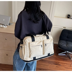 Detail of off-white large canvas travel bag with zip pockets and adjustable straps