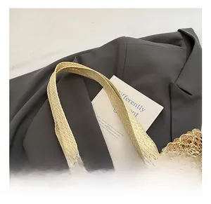 Close-up of a hollow out straw woven tote bag featuring wide beige handles and mesh texture