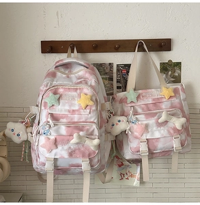 Detail of pink tie-dye backpack set with cute plush charms on a wooden rack