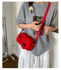Detail view of red nylon crossbody bag featuring black buckle and Moborn brand tag