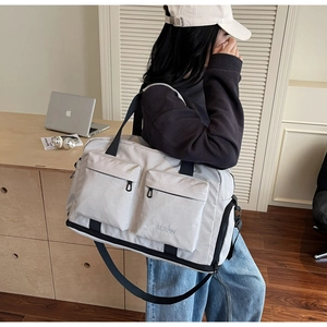 Detailed side view of a large light grey travel bag with multiple pockets worn by a person