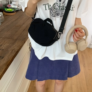 Detail of a black nylon crossbody bag with adjustable strap on a casual summer outfit