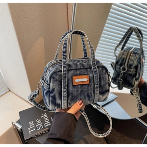 Detail view of retro blue washed denim handbag with leather patch and silver hardware