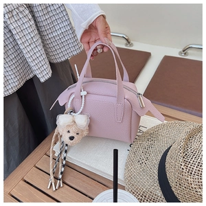 Détail du sac à main en cuir rose avec breloque ours mignon sur une table basse