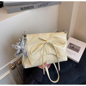 Détail du sac plissé crème avec nœud décoratif et pendentif étoile en argent