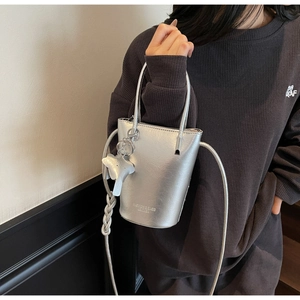 Silver metallic leather bucket bag with top handles and cute elephant charm on a model