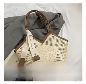 Detail of hollow-out tote bag with brown leather trim and canvas ribbon handle decoration