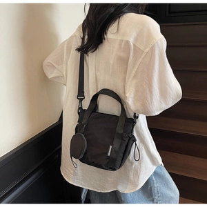 Detail of black nylon bucket bag with round coin purse and wide adjustable shoulder strap