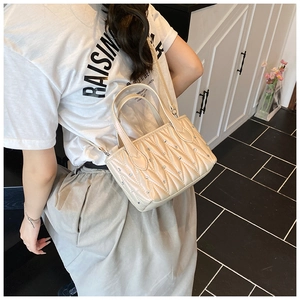 Detail of beige quilted shoulder bag with wave stitching and sparkling rhinestone accents
